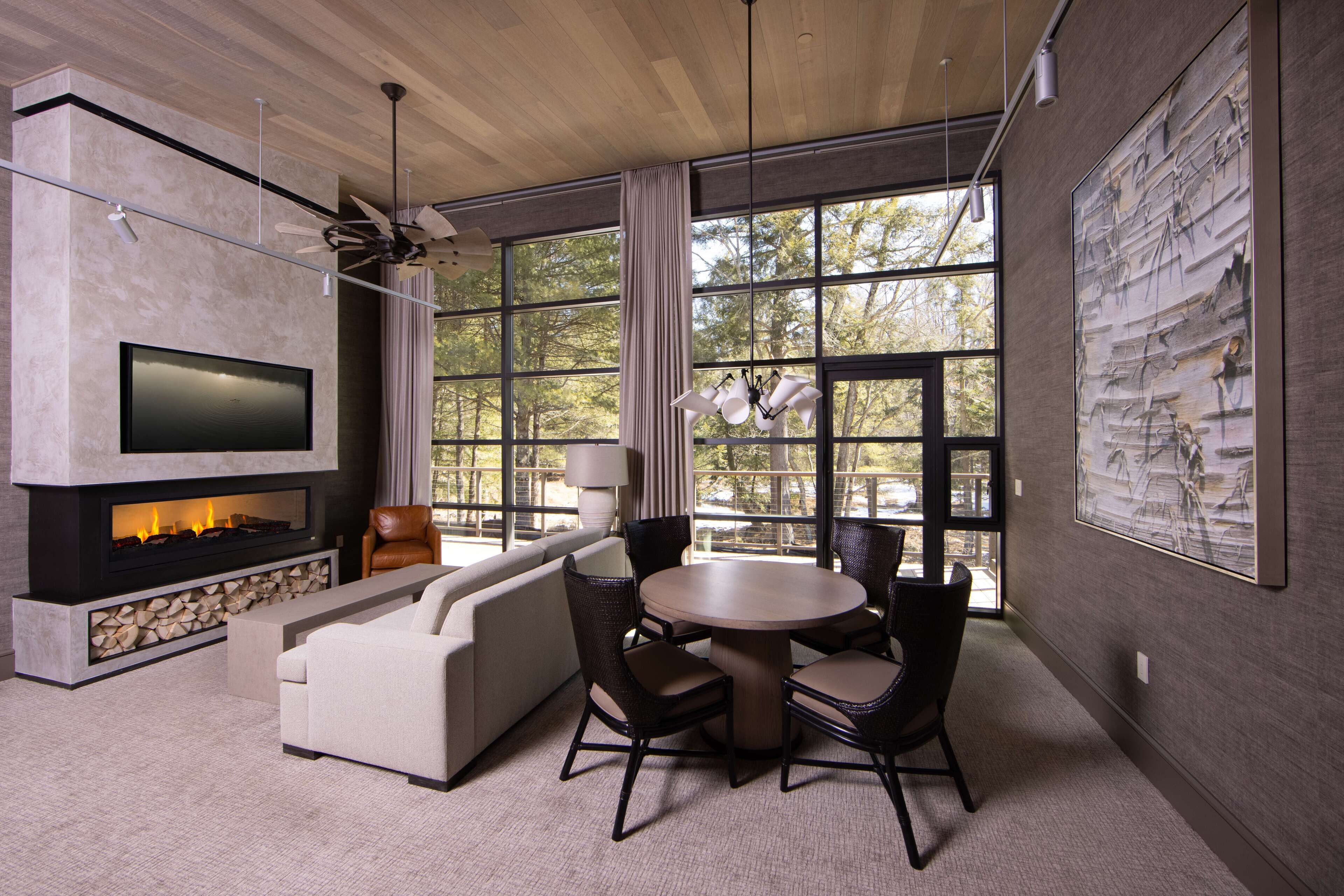 Una sala de estar moderna con chimenea, televisor grande y comedor con sillas y una mesa.