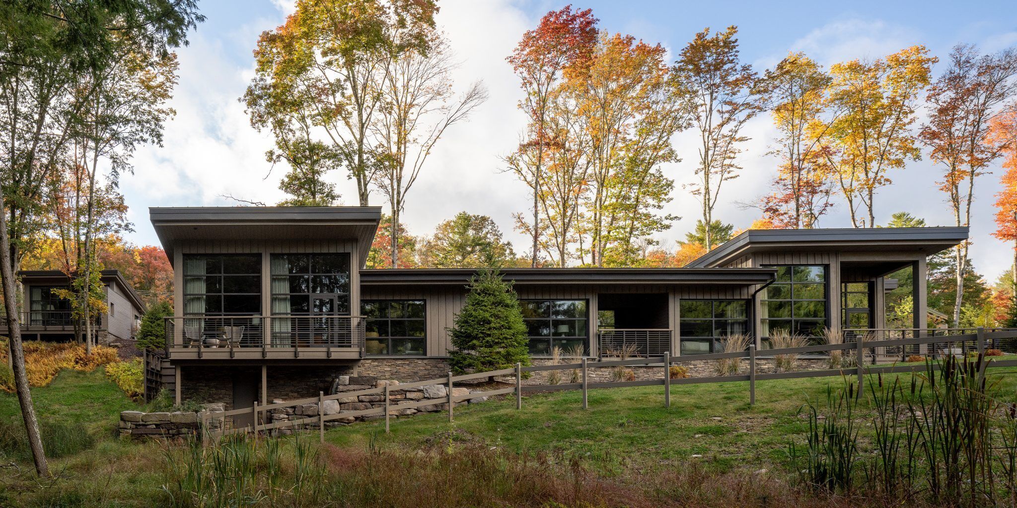 A modern two-story house with large windows and a stone staircase leading to the entrance.