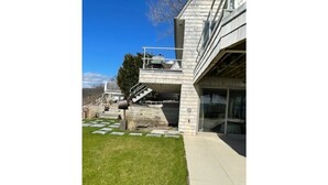 A modern building with a flat roof, a large glass window, and a concrete staircase leading to a second floor. - Sunset Bluff: Breathtaking views of LI Sound. (Northport)