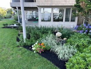 A modern two-story house with a well-maintained garden featuring various plants and flowers.