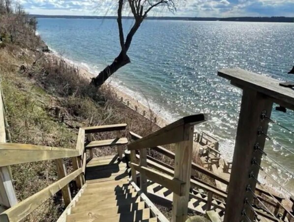 A wooden staircase leading down to a beach with a clear view of the water.
