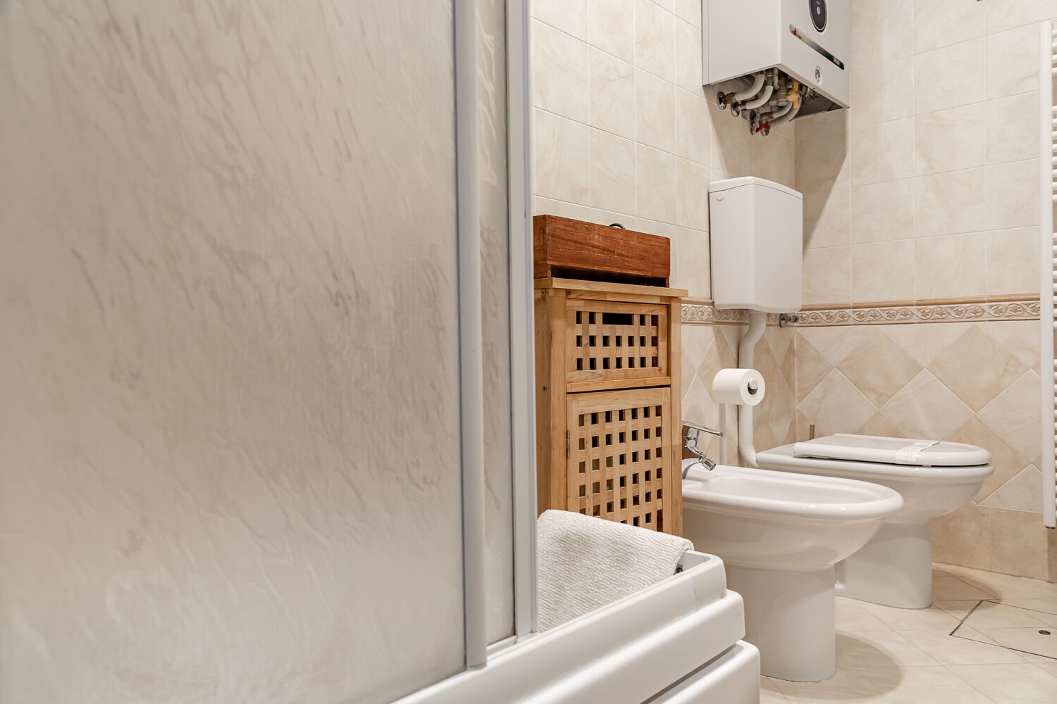 Une salle de bain avec deux toilettes, un meuble en bois et un porte-serviettes.