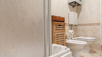 Une salle de bain avec deux toilettes, un meuble en bois et un porte-serviettes.