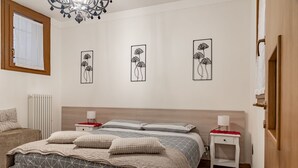 Une chambre à coucher comprenant un lit, des tables de chevet, un radiateur et des œuvres d’art murales.