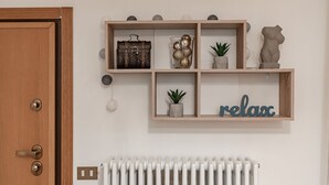Une porte en bois avec une poignée en laiton, un radiateur blanc et une étagère murale ornée d’objets décoratifs et d’une pancarte indiquant « détente ».