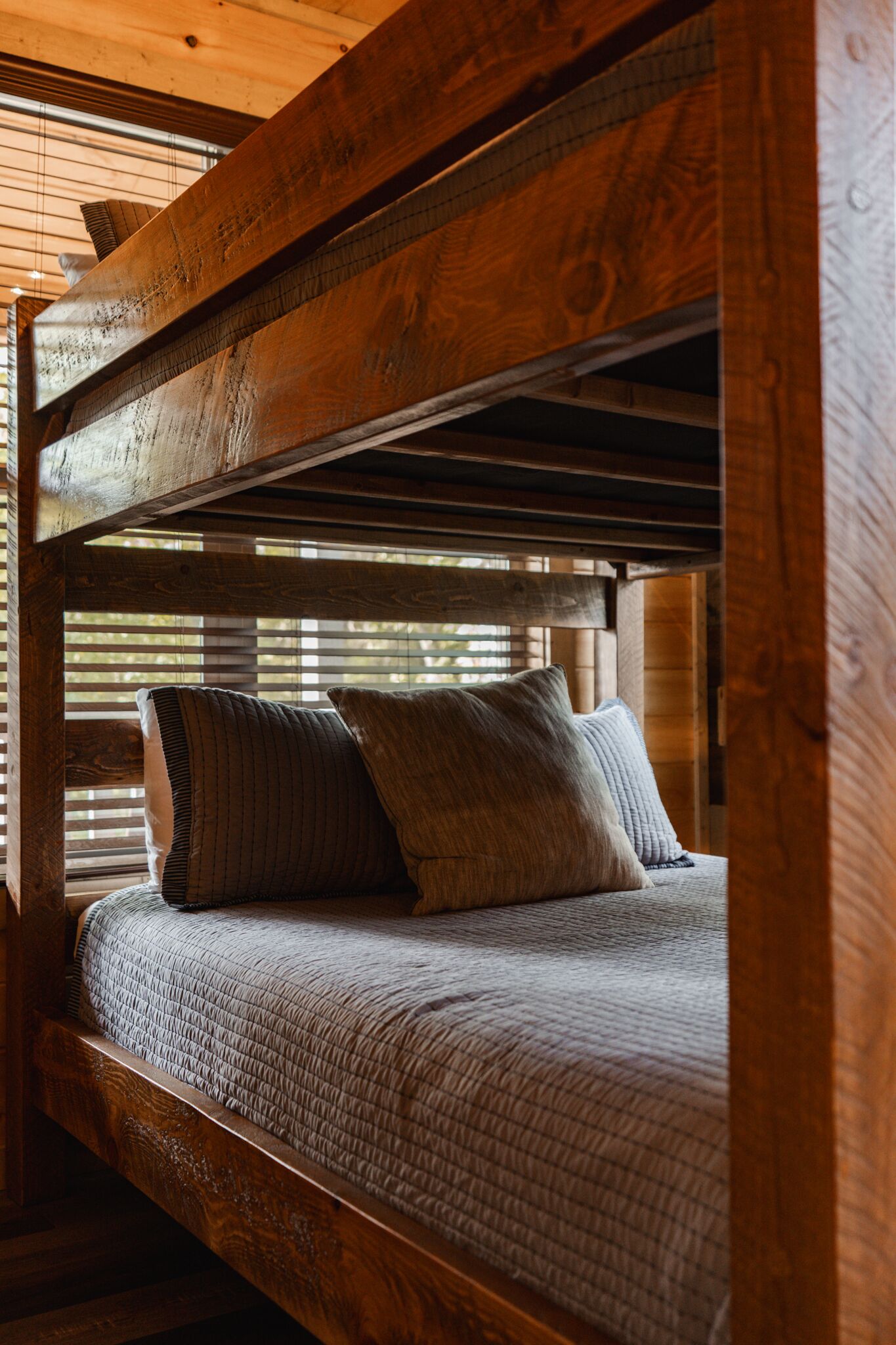A bunk bed with a wooden frame and a quilted mattress.
