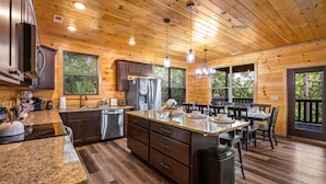 A spacious kitchen with granite countertops, wooden cabinets, and a central island. - Planning a Smokey Mtn Family Vacation? Stay Here! They will love you for it. (Sevierville)