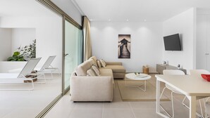 A modern living room with a beige sofa, a round coffee table, and a dining table. - MAGNIFICENT NEW APARTMENT ADAMA JARDINES DE LOS MENCEYES (Palm-Mar)