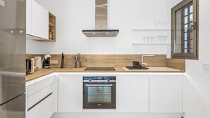 A modern kitchen with white cabinetry, a built-in oven, a stainless steel range hood, and a wooden countertop. - MAGNIFICENT NEW APARTMENT ADAMA JARDINES DE LOS MENCEYES (Palm-Mar)