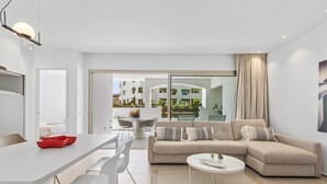 A modern living room with a sofa, coffee table, and dining area. - MAGNIFICENT NEW APARTMENT ADAMA JARDINES DE LOS MENCEYES (Palm-Mar)