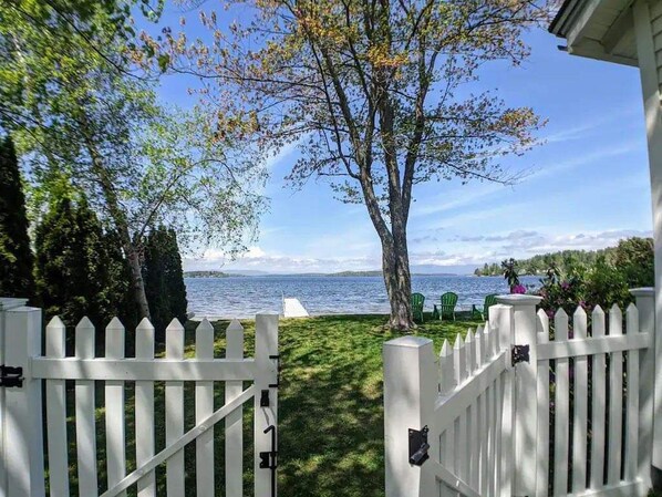 Stroll through a serene garden, surrounded by a tranquil body of water and a picturesque white picket fence.