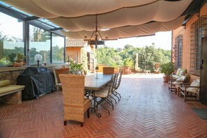 An outdoor patio with a dining table, chairs, and a grill.