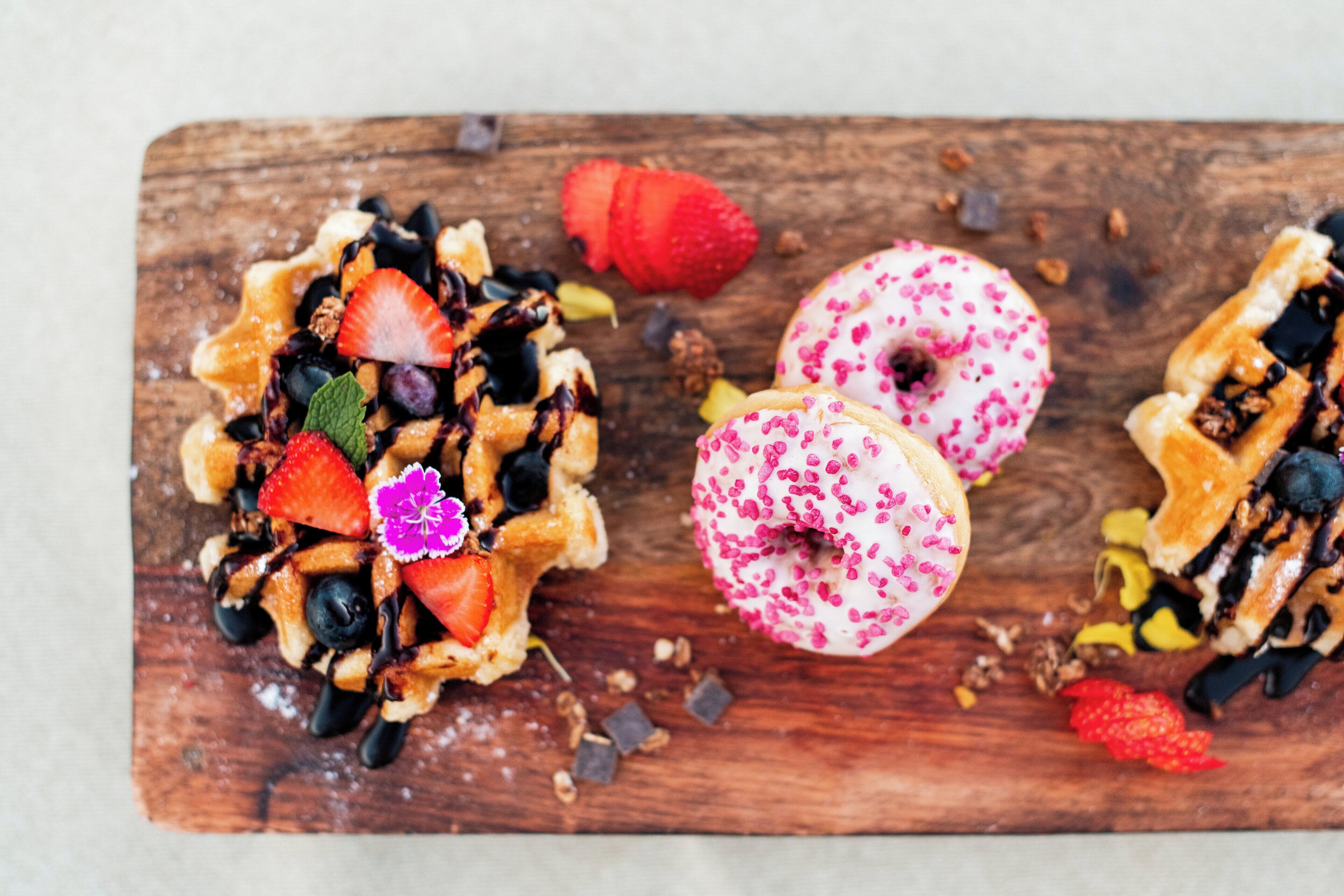 A wooden board with three pastries and a strawberry.
