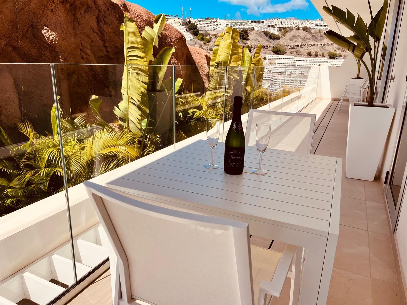 En balkong med ett bord, två vinglas och en flaska ProVeto-vin.