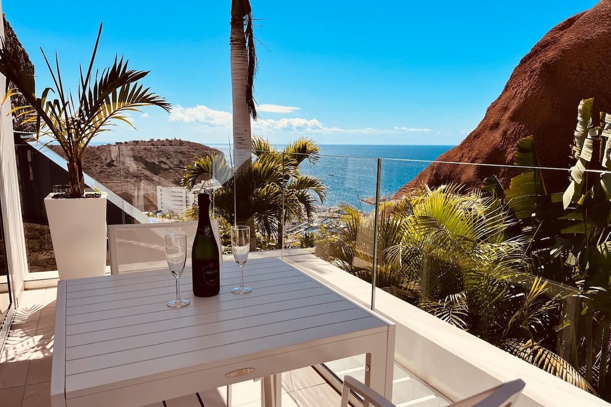 A terrace with a table, two wine glasses, and a bottle of wine.