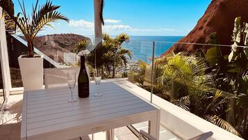Una terrazza con un tavolo, due bicchieri da vino e una bottiglia.