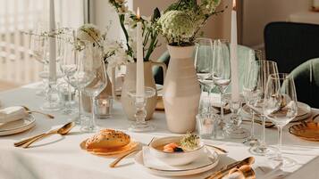 A table set for a meal with clear glassware, white plates, and gold cutlery.
