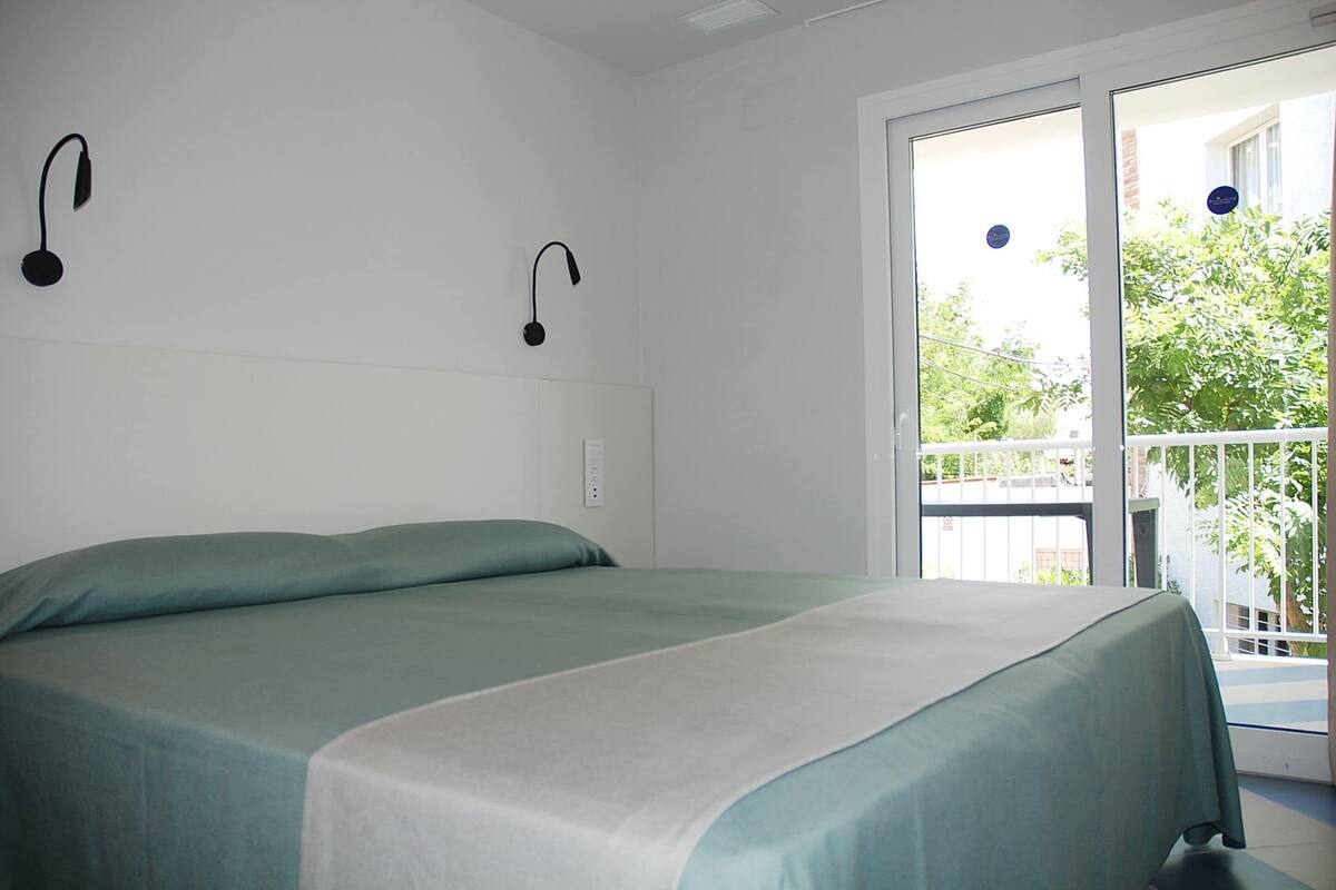 A room with a bed, a window, and a balcony.