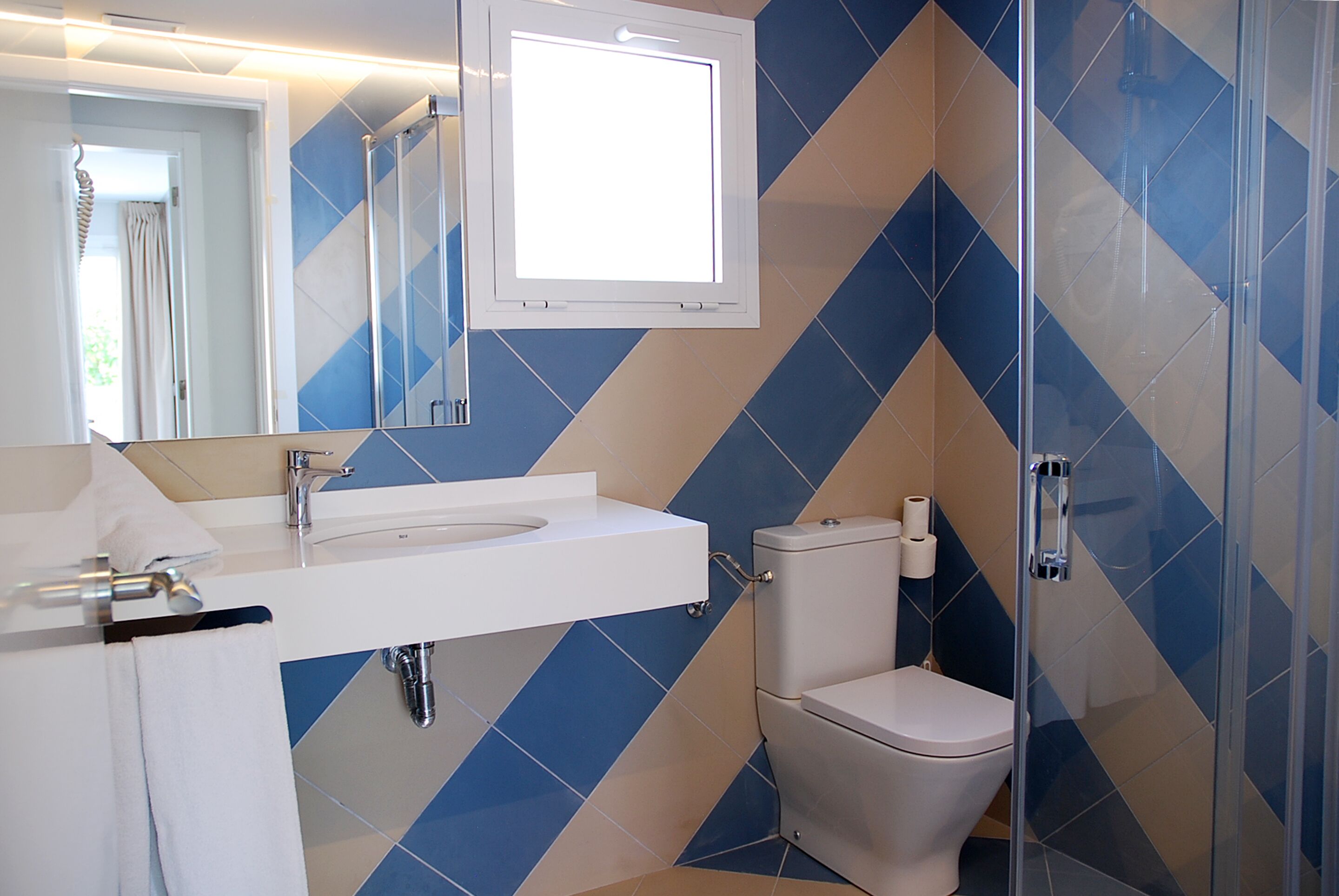 A bathroom with a white sink, mirror, and toilet, and a shower area with a glass door.