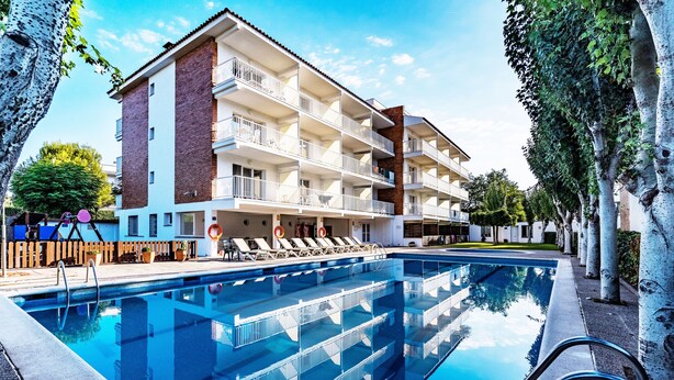 A multi-story hotel with a swimming pool, outdoor seating, and a brick facade. - Sunway Arizona (Sitges)