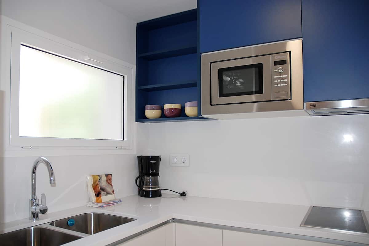 A kitchen with a built-in microwave, a coffee maker, and a sink.