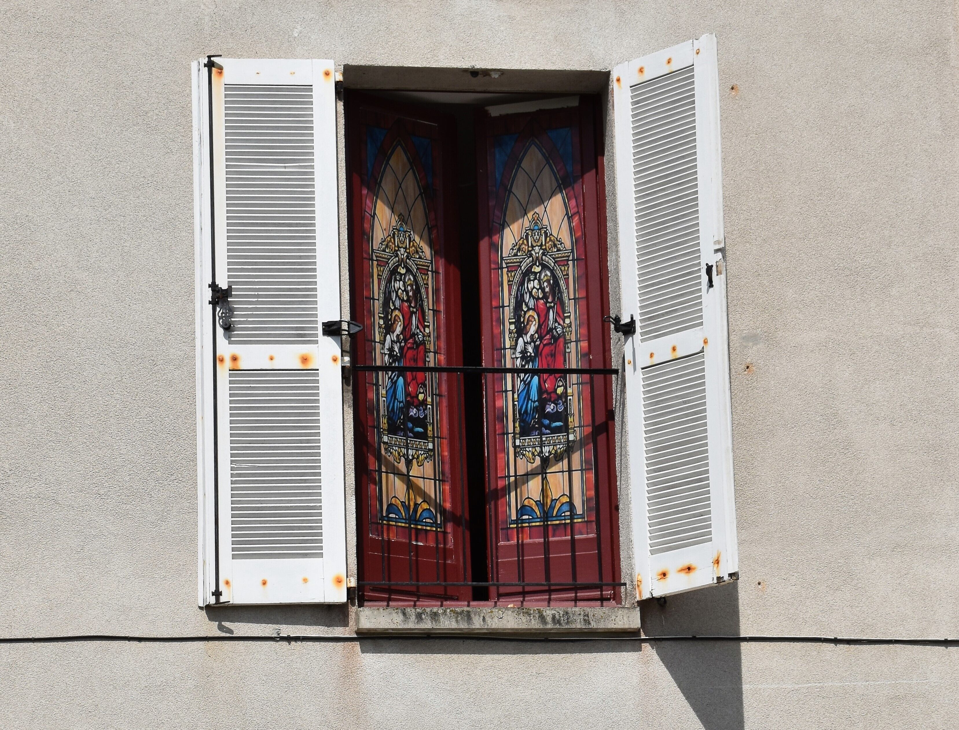L'ingresso di un edificio con una finestra a vetri colorati e un cancello in metallo.