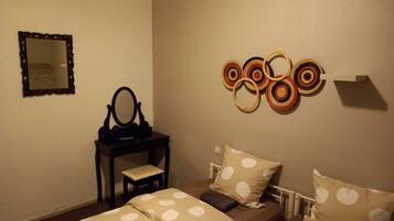 Une chambre avec deux lits, une petite table avec un miroir et un élément décoratif mural.