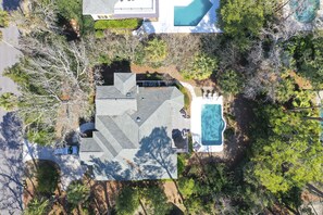 Vista aerea di una proprietà residenziale con piscina, patio coperto e giardino curato.