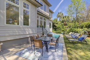 A two-story house with a covered patio area featuring a pool, outdoor seating, and a staircase leading to the upper floor. - 3 Cottage Court (Hilton Head Island)