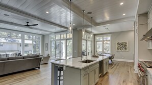 Una cocina espaciosa con una isla grande, electrodomésticos modernos y abundante luz natural gracias a amplias ventanas.