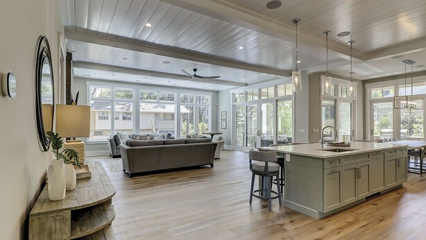 Una cocina amplia con una isla grande, piso de madera y abundante luz natural gracias a ventanas grandes.