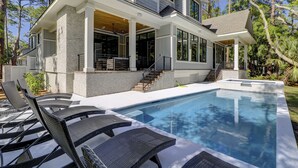 Una casa moderna con piscina, zona de estar exterior y patio cubierto.