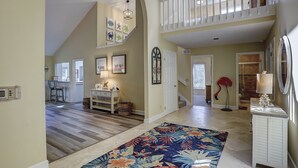 A spacious hallway with a wooden floor, a colorful rug, and a staircase leading to an upper level. - 6 Dinghy (Hilton Head Island)
