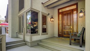 A house with a wooden front door, a porch with steps, and two wall-mounted lanterns. - 6 Dinghy (Hilton Head Island)