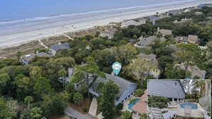 An aerial view of a coastal residential area with houses, a beach, and a sign for a vacation company. - 30 Pelican (Hilton Head Island)
