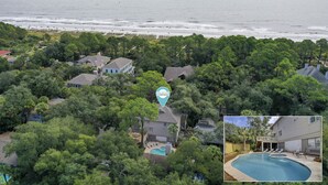 An aerial view of a residential area with houses surrounded by dense greenery, a visible swimming pool, and a beach in the background. - 1 Sea Oak (Hilton Head Island)