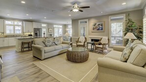 A spacious living room with a sofa, coffee table, and chairs, a kitchen in the background, and a ceiling fan. - 1 Sea Oak (Hilton Head Island)
