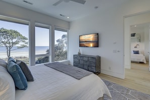 Un dormitorio con una cama grande, vistas a la playa y un televisor en la pared.