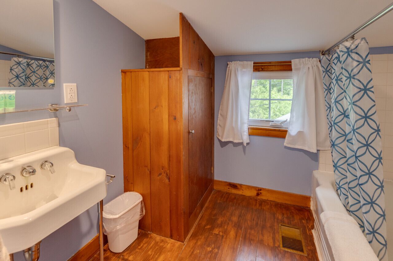 Ein Badezimmer mit Holztür, Waschbecken in Weiß und einer Badewanne.
