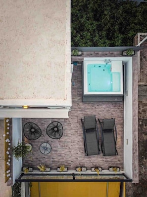Eine Dachterrasse mit Whirlpool, zwei Liegestühlen und einem kleinen Tisch.