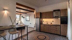 A modern kitchen with wooden cabinets, a stainless steel refrigerator, and a dining area with stools.