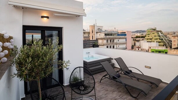 A rooftop terrace with a hot tub, lounge chairs, and potted plants.