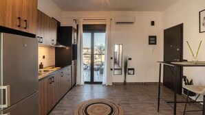 A modern kitchen with wooden cabinets, a stainless steel refrigerator, and a dining area with a table and chairs.