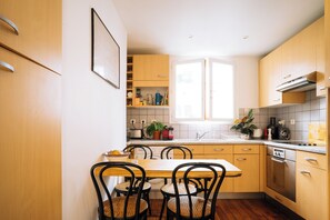 A modern kitchen with wooden cabinets, a dining table with chairs, and a window providing natural light. - Spacious & Quirky 1BD flat 10 mins to Sacré Coeur (Paris)