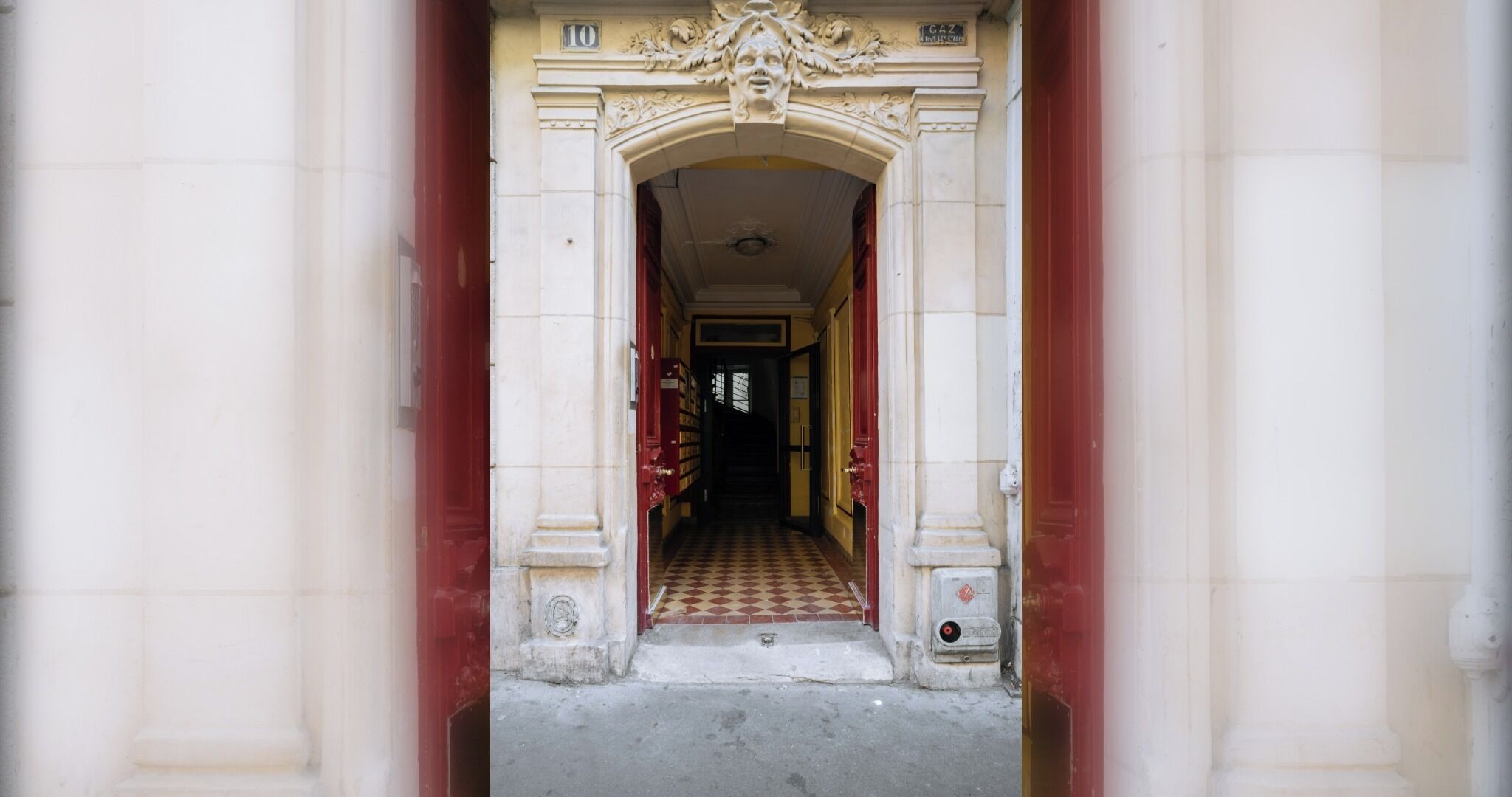 Une entrée en arc surmontée d’un sol à carreaux menant à un bâtiment.