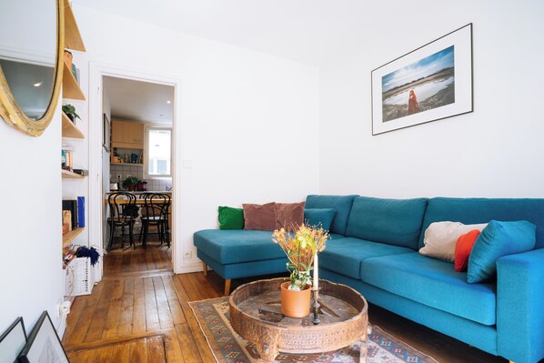 A living room with a blue sofa, a coffee table with a plant, and a framed picture on the wall.