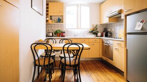 Een moderne keuken met houten kastjes, een roestvrijstalen koelkast en een eettafel met vier stoelen.