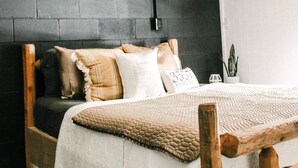 Un lit en bois surmonté d’une couette blanche et marron, un mur noir et une tête de cerf fixée au mur.