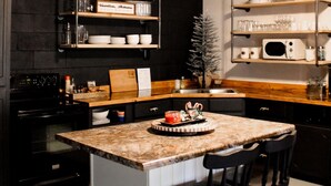 Une cuisine moderne dotée d’un îlot central, de tabourets de bar, d’un four à micro-ondes et d’une machine à café.