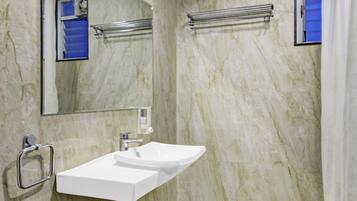 A bathroom with a marble wall, a white sink, a mirror, and a shower curtain.